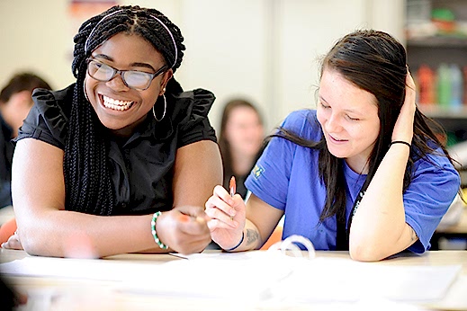 Two young women in a classroom smiling