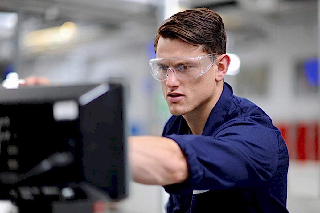 Man in protective goggles adjust the settings on some heavy machinery