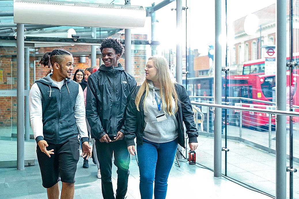 A group of students enter the college as London whizzes by in the background