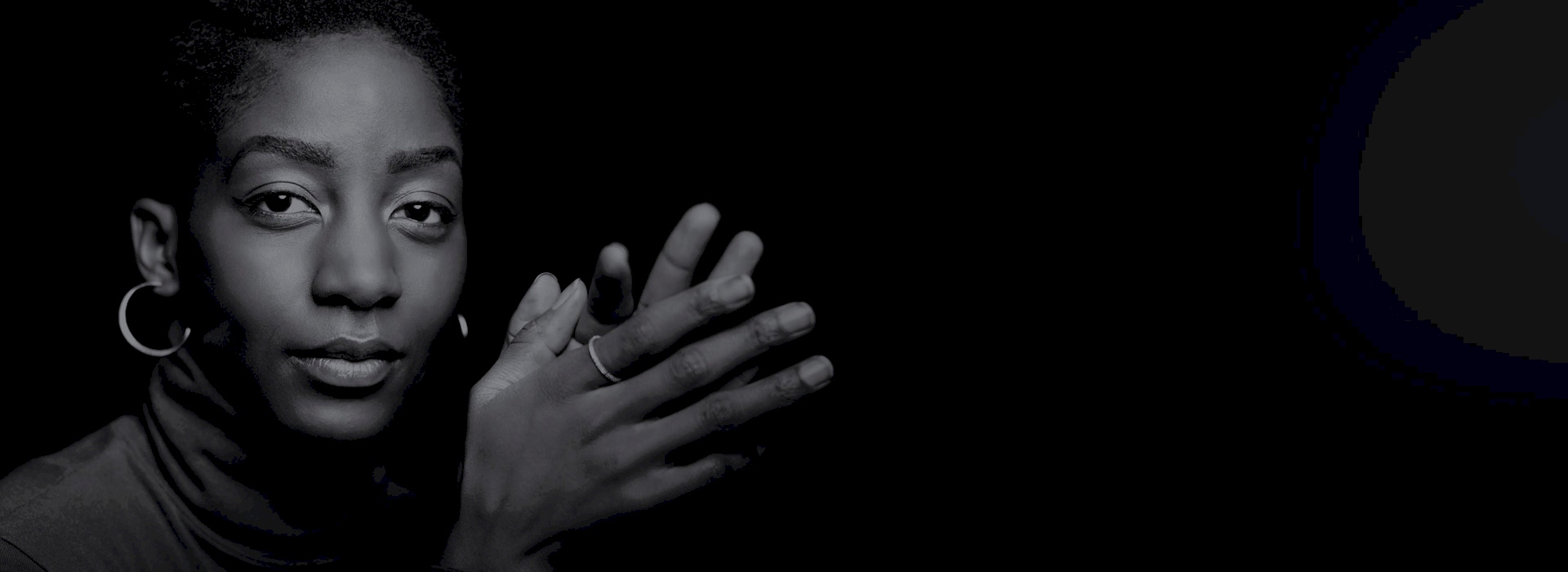 A man looks out at us from deep shadow considering his options as he strokes his chin