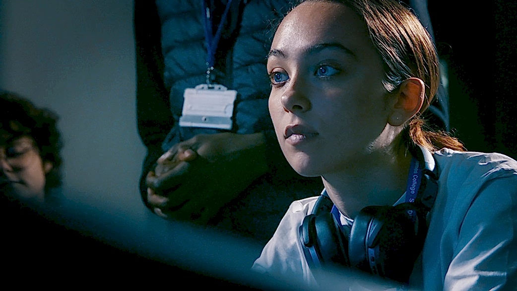 A young woman at a recording mixing desk with an expression of intense concentration