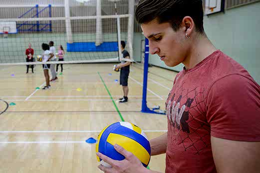 A young man gets his mind into the zone as he prepares to serve in a game of softball on court in the sports hall